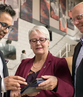 Online tool will help Islanders reduce energy costs Photo shows three people looking at an app on a tablet
