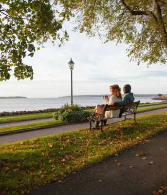 Fall in Prince Edward Island A man and a woman sit on a bench overlooking the harbour in Victoria Park in a fall setting.