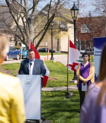 image of people in a park listening to a person behind a podium speaks