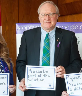 Three people holding signs reminding us to speak out against family violence