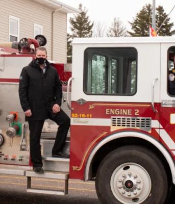 Province supports PEI Firefighter Association Fire School image of three people standing on a fire truck