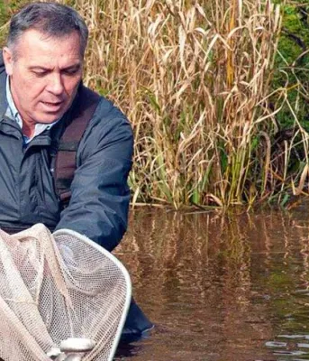 Fish added to Island waterways Minister Mitchell releasing fish into a river