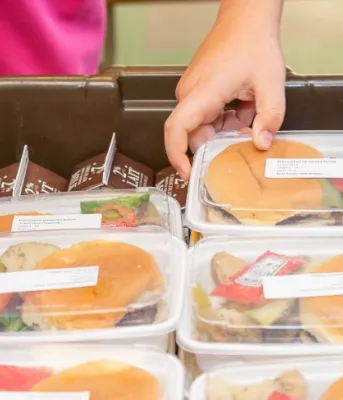 A child reaches for a pre-made lunch