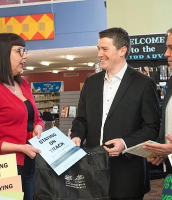 More help available for mental health and problem gambling Five people standing in a library holding some small signs about staying mentally on track