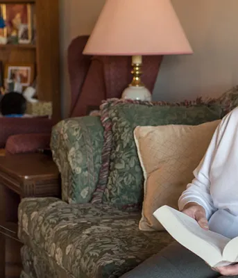 Seniors living at home get more help from province Photos shows Gladys Dirani sitting in her living room with a book on her lap.