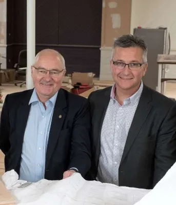 Four people at a work table holding design plans