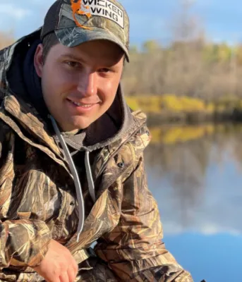 image of a person in hunting gear with a pond in the background