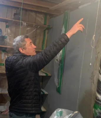 Photo shows a man installing insulation in a home