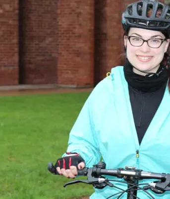 Jenny Melanson Female biker standing in front of workplace with her bike.