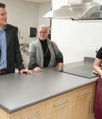 First Three Oaks teachers, students move into renovated spaces Photo shows ministers speaking with students in the newly renovated culinary arts kitchen.