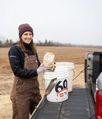 Kyra Stiles holds a paper bag of soil next to a truck