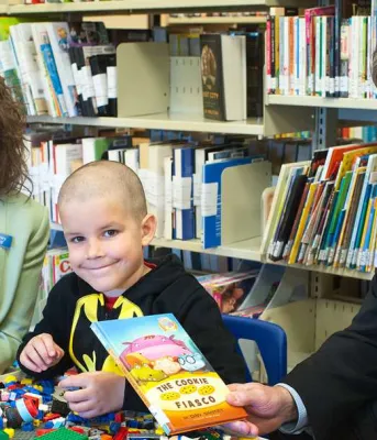 Libraries end overdue fines for children A man and woman with a school aged child holding a book