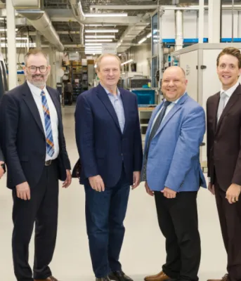 Eight officials from the federal and provincial governments and MDS Technologies standing inside a facility