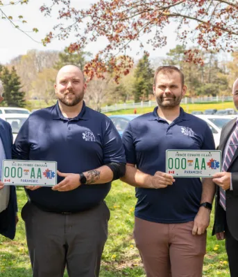  image de quatre personnes debout épaule contre épaule tenant des plaques d&#039;immatriculation de voiture