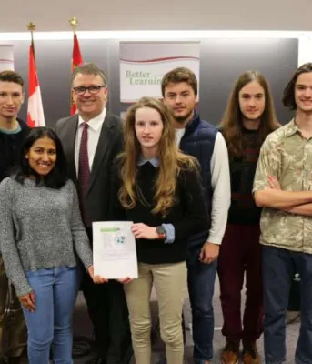 Island students show significant progress in latest PISA assessment Minister Curries stands with a group of high school students