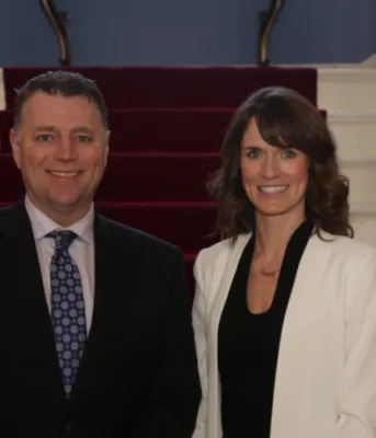 Premier King stands with Minister Jameson in front of the stairway in Government House