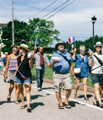 image de personnes marchant dans une petite rue de campagne en été et chacune tenant de petits drapeaux