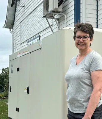 image of a person standing by a large generator outside a community hall