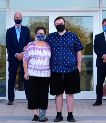 People standing apart in front of glass doors