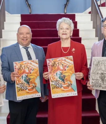 Rendez-vous de la Francophonie celebrates 26 years image of four people inside a buidling standing shoulder to shoulder holding posters with a staircase in the background