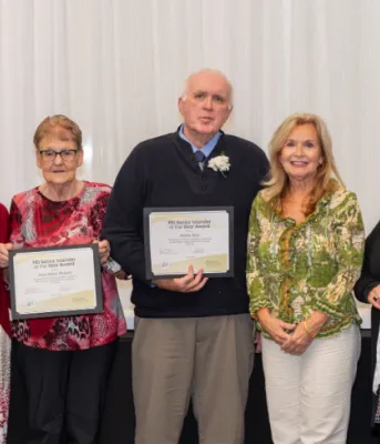 image of a group of people standing shoulder to shoulder in a room with a white curtain behind them and holding certificates in their hands