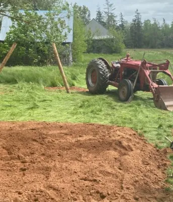 image of a person in a garden beside a field and tractor
