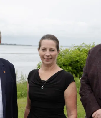 Province announces new 9km active transportation trail in St. Peter’s image of three people standing shoulder to shoulder with a bay of water in the background