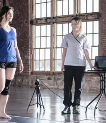 Woman is walking on a mat that measures her foot pressure points, while another woman looks on