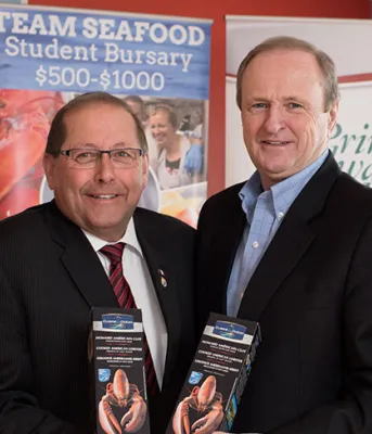 Team Seafood expands student jobs Four people standing in Team Seafood Student Bursary signs.