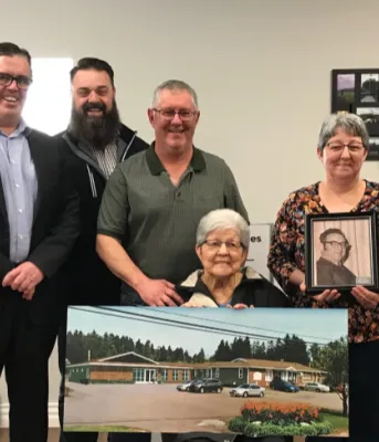 Minister Myers and four Islanders stand behind a woman sitting holding a large photo of the proposed Tignish co-op expansion