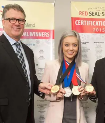 People standing in front of pop-up banners with middle person displaying medals won at a national competition.
