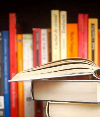 image of an open book in front of a library book shelf