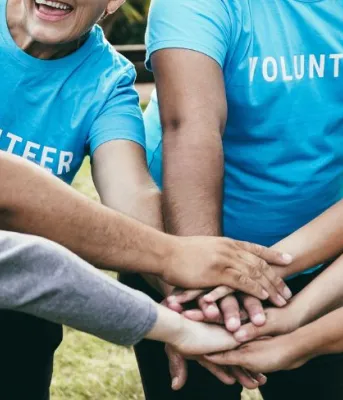 Volunteers smile and put their hands together 