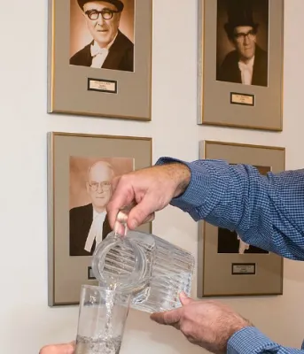 Water Act debated in legislature Photo shows Dean Stewart pouring a glass of water for Minister Robert Henderson