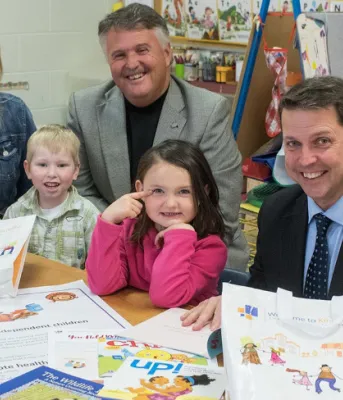 Schools welcome children entering kindergarten next year Children and adults sitting at school table with books